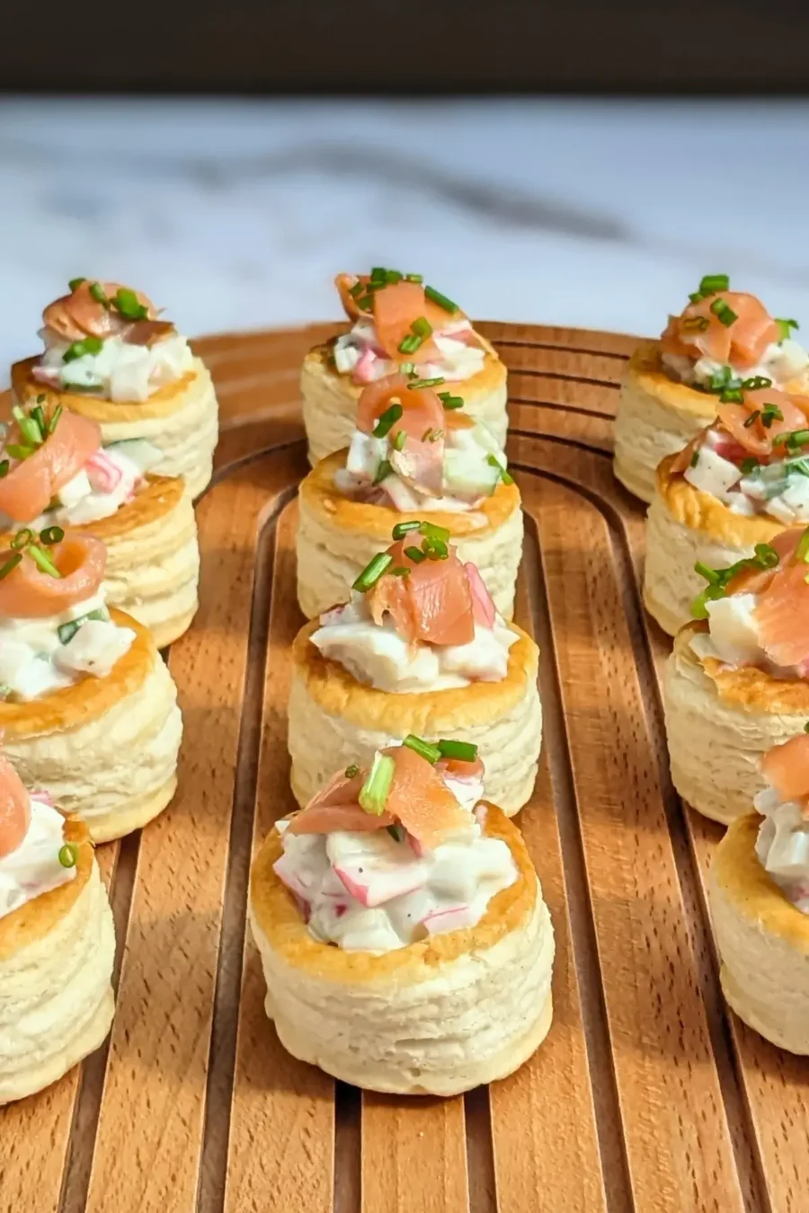 Surimi vol au vent appetizers - puff pastry vol au vent shells filled with a surimi, cucumber, and mayonnaise salad topped with smoked salmon and fresh chives. 