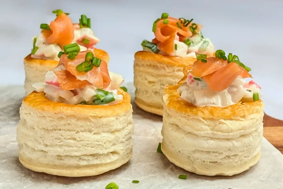 Surimi vol au vent appetizers - puff pastry vol au vent shells filled with a surimi, cucumber, and mayonnaise salad topped with smoked salmon and fresh chives.