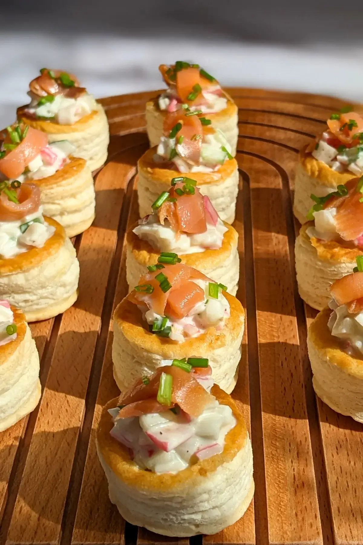 Surimi vol au vent appetizers - puff pastry vol au vent shells filled with a surimi, cucumber, and mayonnaise salad topped with smoked salmon and fresh chives. 