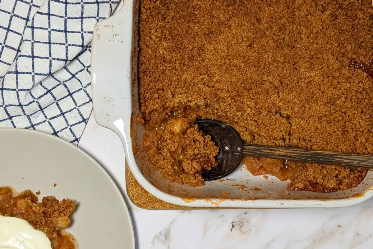Fruit-filled apple crumble with a golden, crumbly topping and chunks of rhubarb and apple at the bottom.