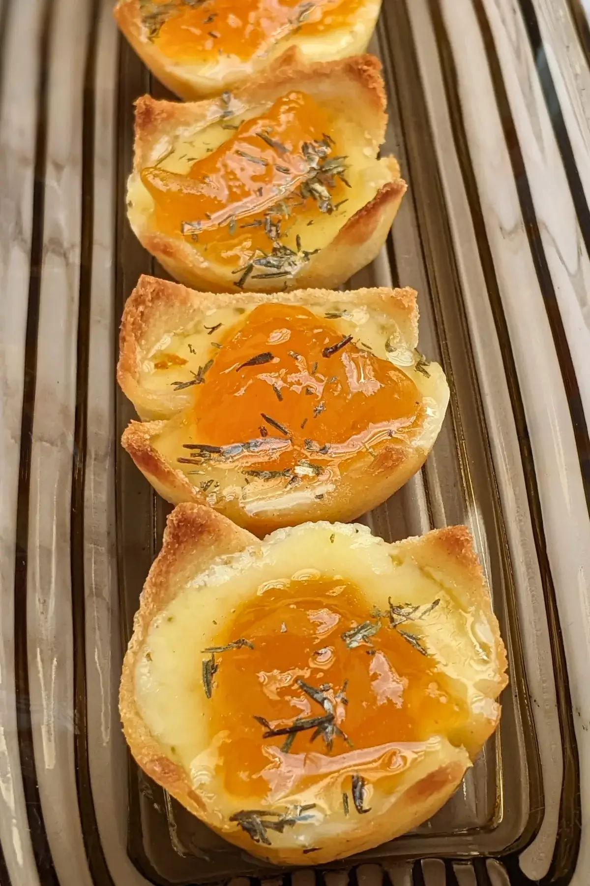 Cheddar cheese and apricot jam appetizer bites - mini bread toast cups filled with cheddar cheese, topped with apricot jam and a honey-dryed thyme drizzle.