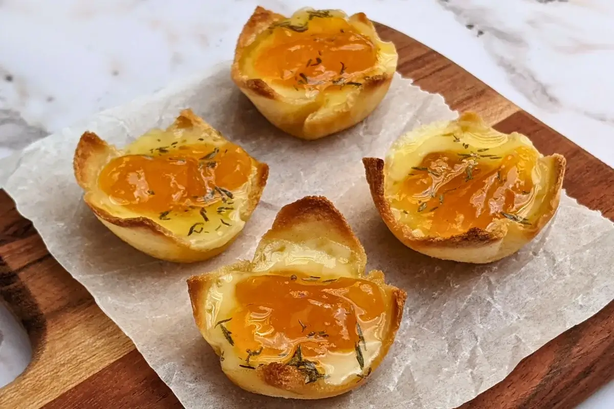 Cheddar cheese and apricot jam appetizer bites - mini bread toast cups filled with cheddar cheese, topped with apricot jam and a honey-dryed thyme drizzle.