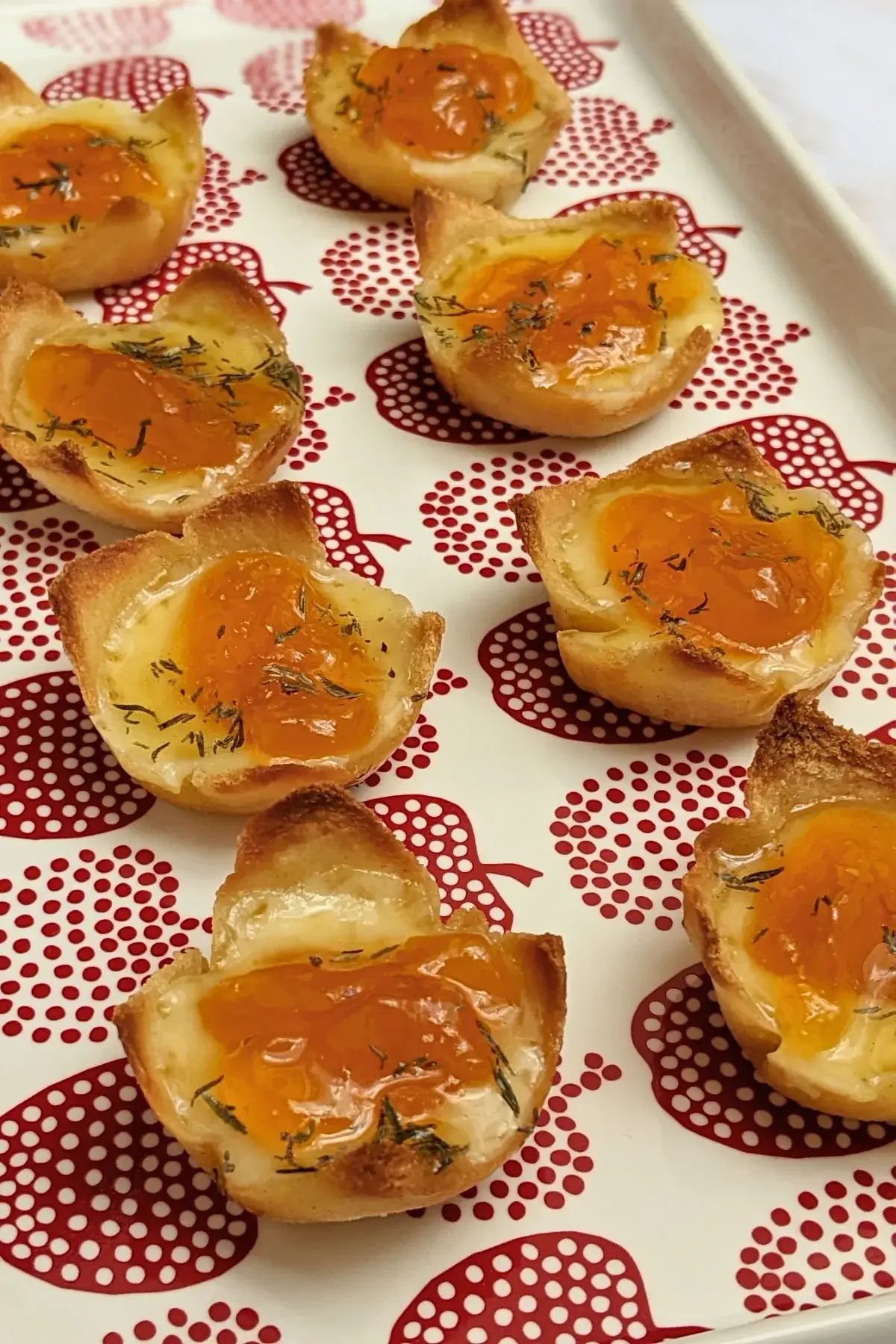 Cheddar cheese and apricot jam appetizer bites - mini bread toast cups filled with cheddar cheese, topped with apricot jam and a honey-dryed thyme drizzle.