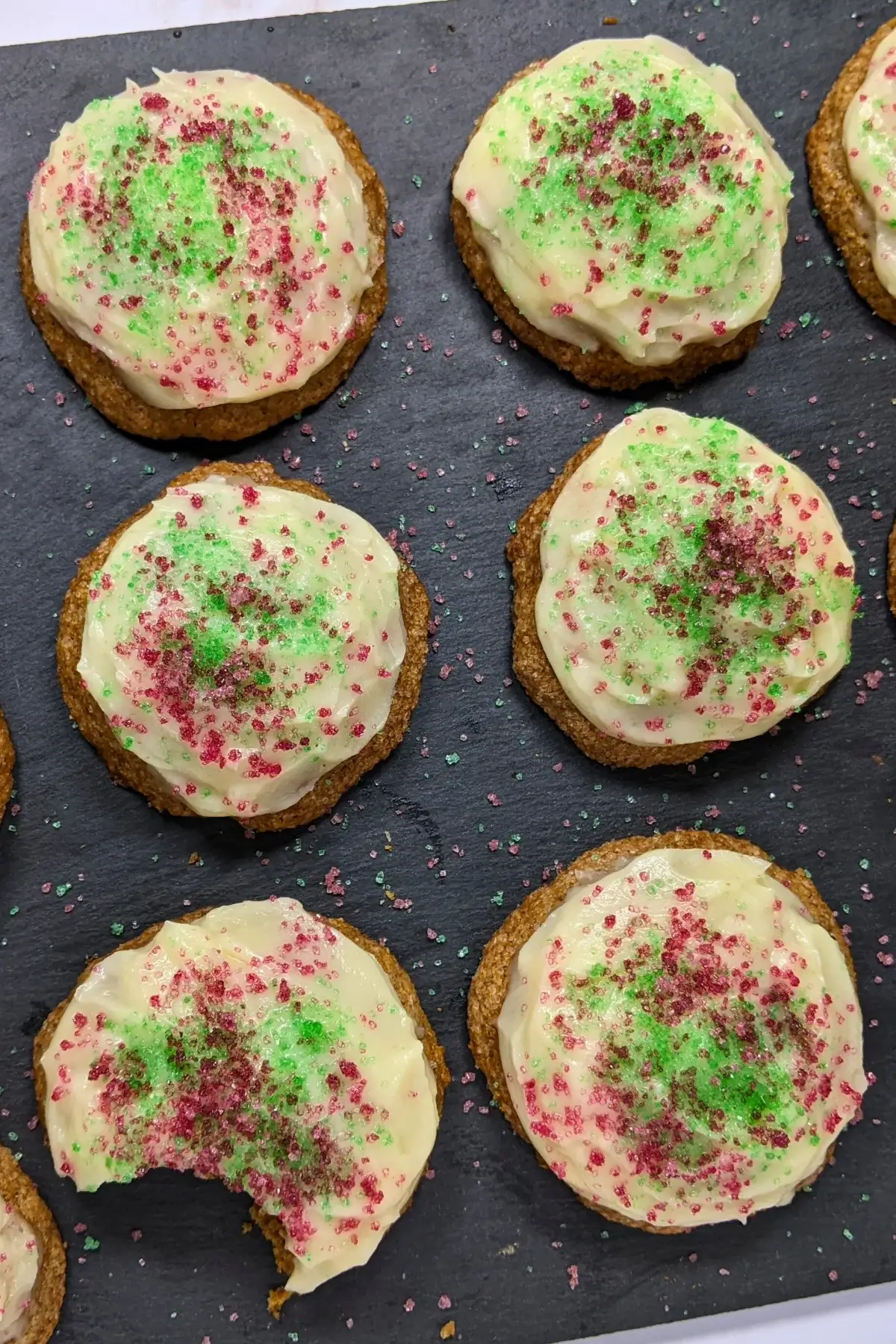Christmas pumpkin sugar cookies made with healthier wholemeal flour and coconut sugar, frosted with a classic butter and cream cheese icing, and decorated with red and green sugar sprinkles.