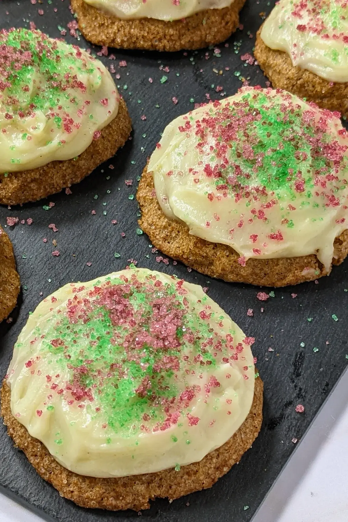 Christmas pumpkin sugar cookies made with healthier wholemeal flour and coconut sugar, frosted with a classic butter and cream cheese icing, and decorated with red and green sugar sprinkles.