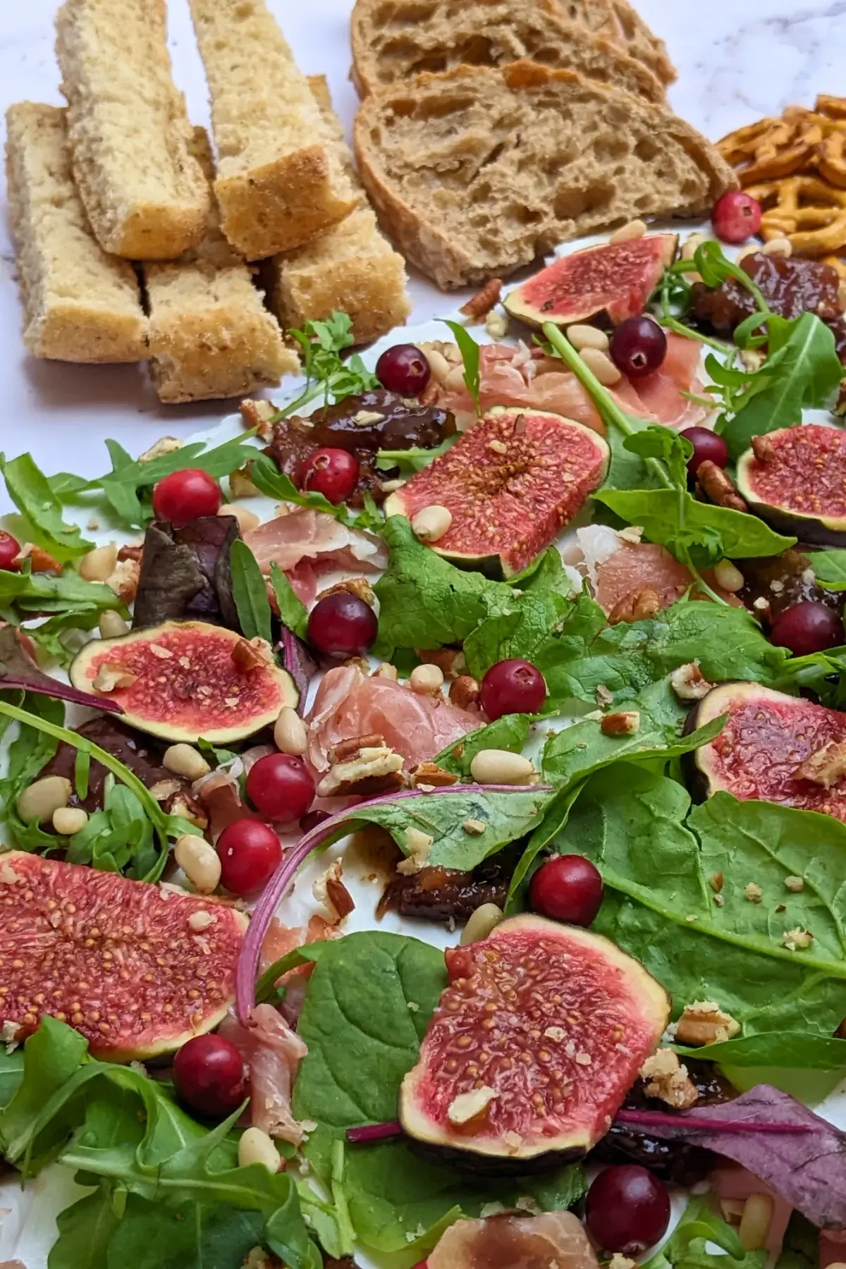 Fig and Goat Cheese Appetizer "Butter" Board With Prosciutto - appetizer board with fresh figs, fig jam, prosciutto, and crunchy toppings sprinkled over a whipped goat cheese spread on a party platter.