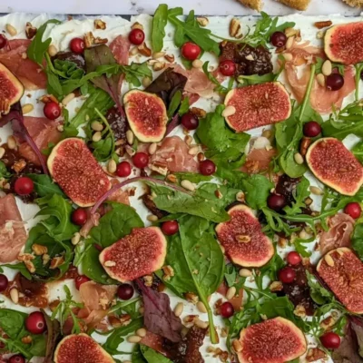Fig and Goat Cheese Appetizer "Butter" Board With Prosciutto - appetizer board with fresh figs, fig jam, prosciutto, and crunchy toppings sprinkled over a whipped goat cheese spread on a party platter.