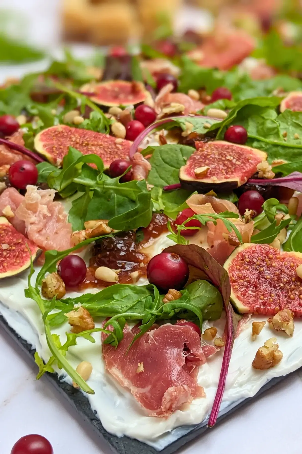 Fig and Goat Cheese Appetizer "Butter" Board With Prosciutto - appetizer board with fresh figs, fig jam, prosciutto, and crunchy toppings sprinkled over a whipped goat cheese spread on a party platter.