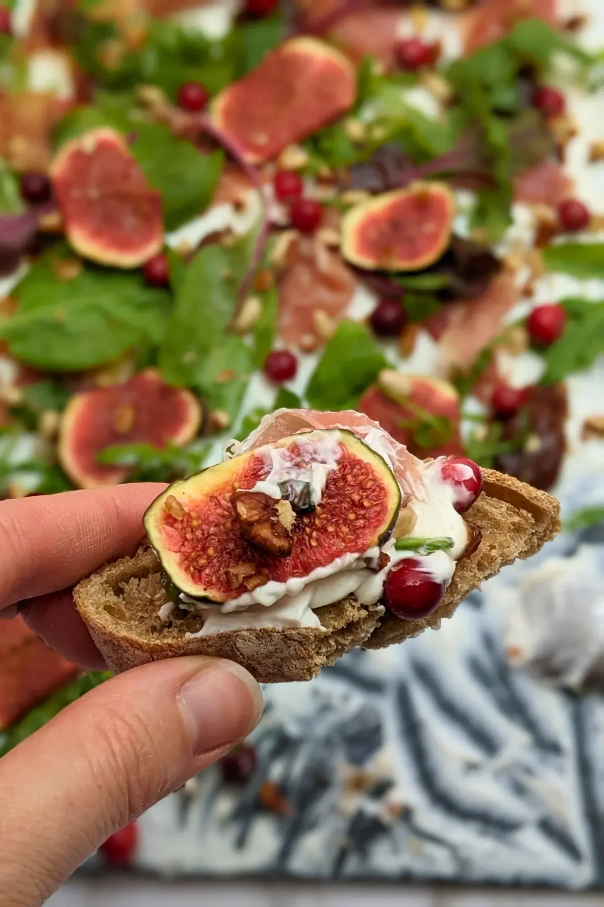 Fig and Goat Cheese Appetizer "Butter" Board With Prosciutto - appetizer board with fresh figs, fig jam, prosciutto, and crunchy toppings sprinkled over a whipped goat cheese spread on a party platter.