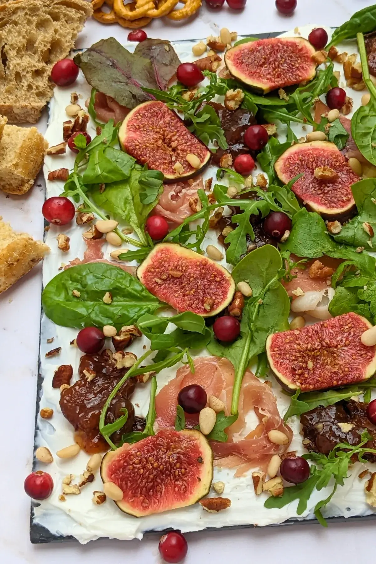 Fig and Goat Cheese Appetizer "Butter" Board With Prosciutto - appetizer board with fresh figs, fig jam, prosciutto, and crunchy toppings sprinkled over a whipped goat cheese spread on a party platter.