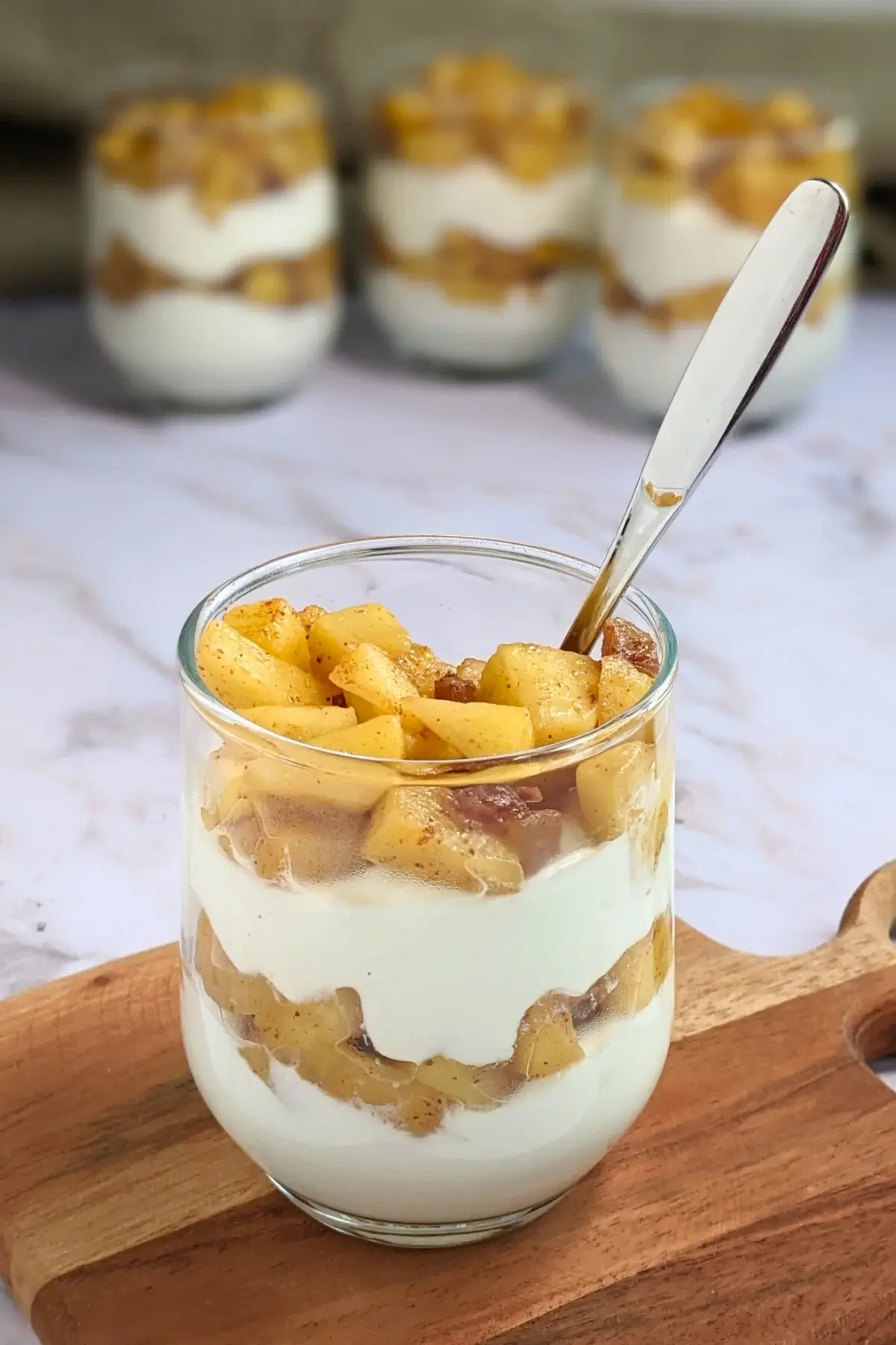 Healthy layered apple parfait dessert with whipped ricotta and cream, topped with stewed apples and chopped dates.