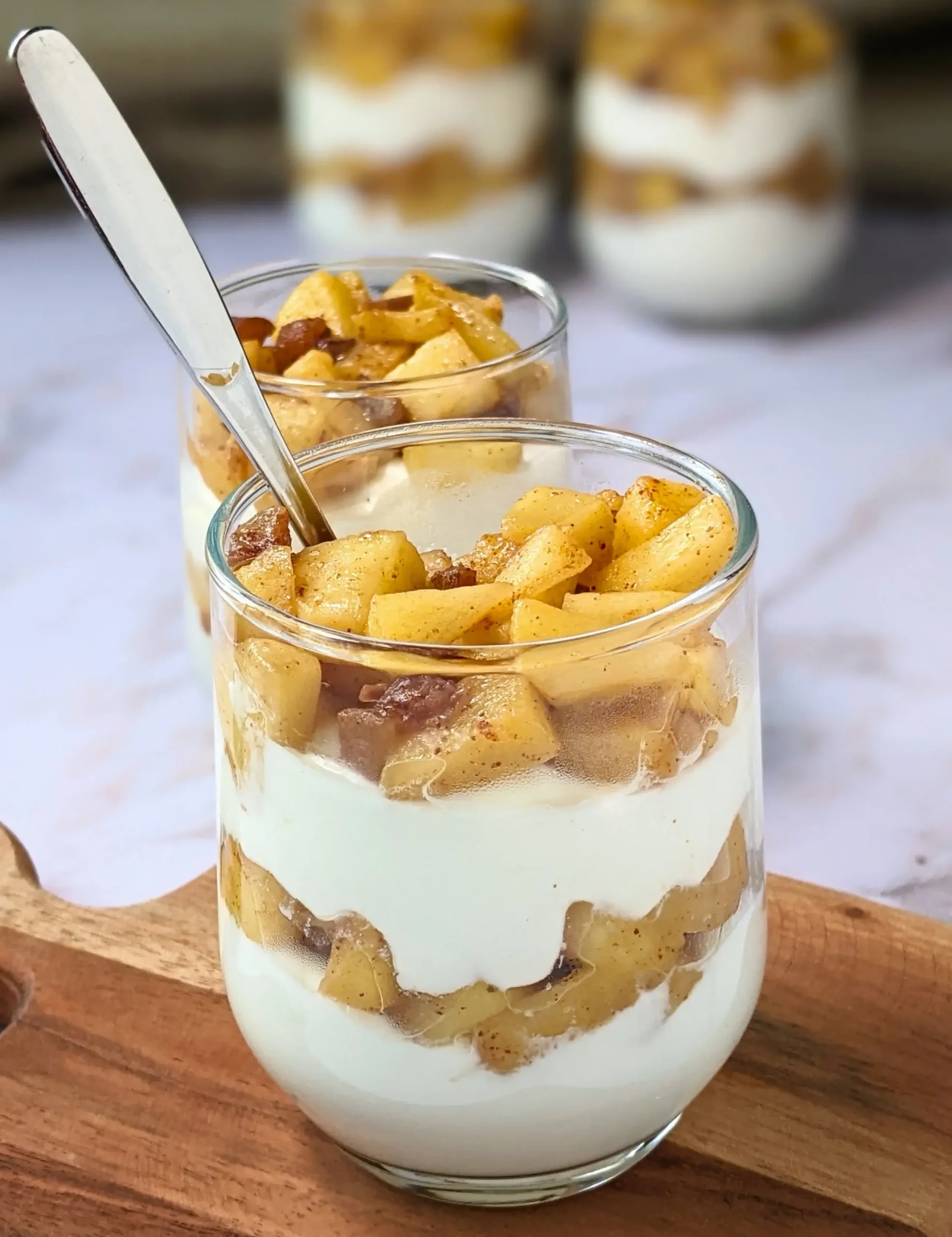 Healthy layered apple parfait dessert with whipped ricotta and cream, topped with stewed apples and chopped dates.
