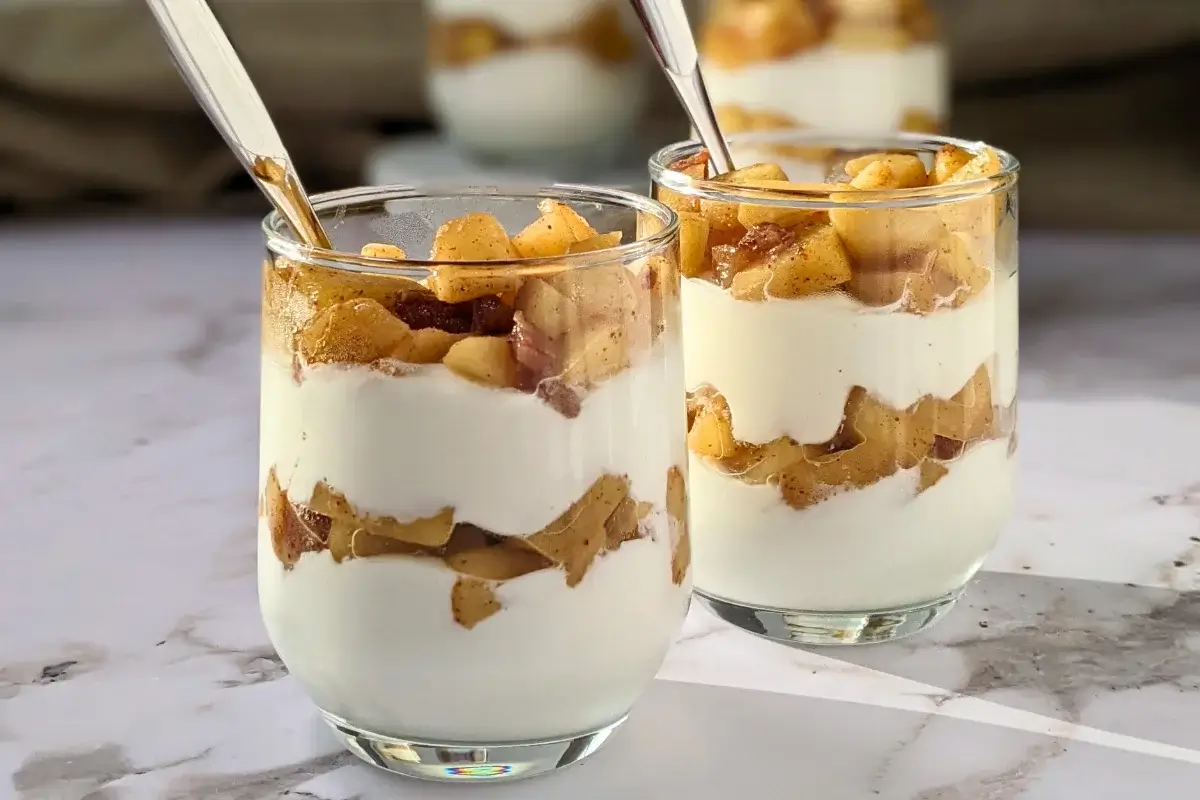Healthy layered apple parfait dessert with whipped ricotta and cream, topped with stewed apples and chopped dates.