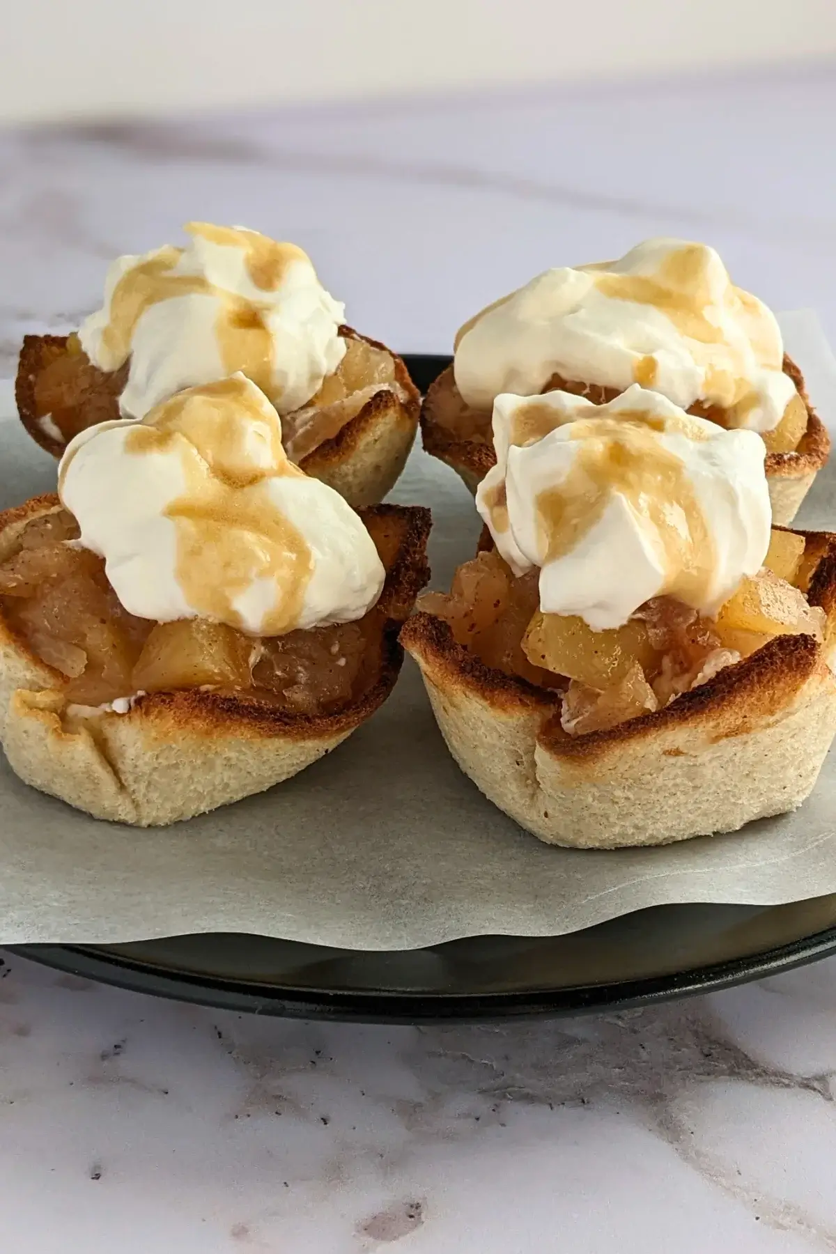 Homemade apple sauce dessert toast cups with whipped cream - Toasted bread cups filled with applesauce and finished with a swirl of whipped cream.