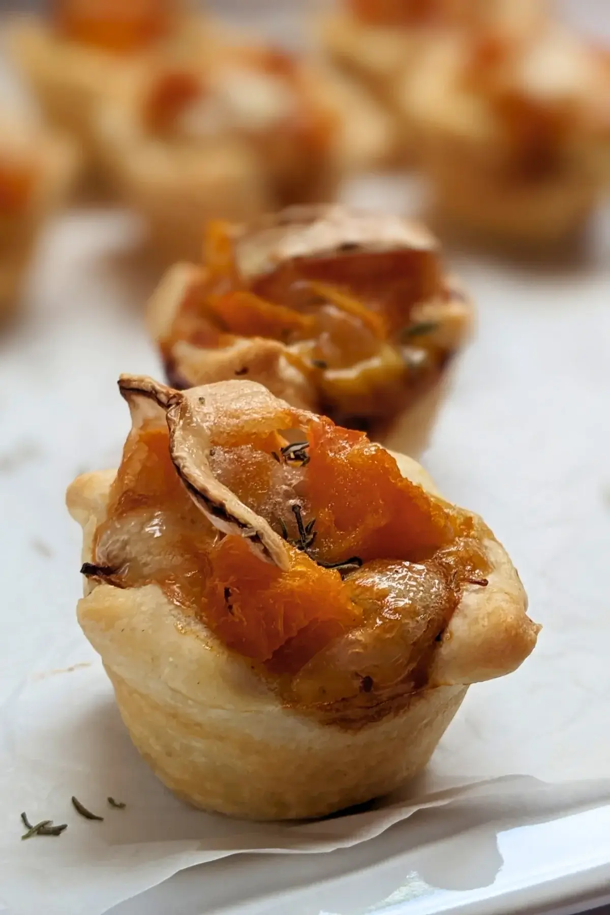 Mini Pumpkin Quiche Cups With Puff Pastry - mini quiche appetizers made in a mini muffin tin with cooked pumpkin, caramelized onions, and crispy ham in puff pastry cups.