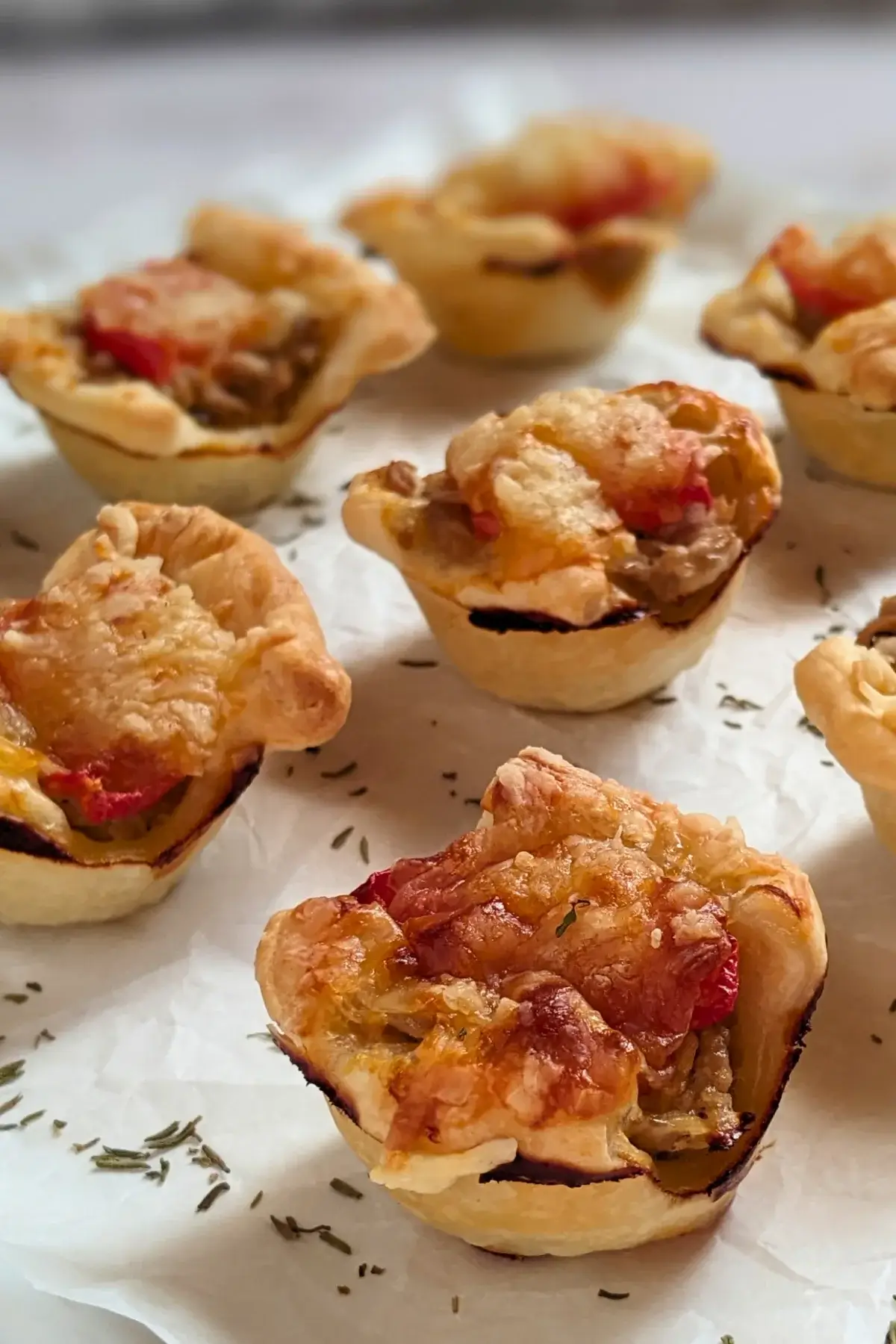 Mini Tuna Tart Cups With Puff Pastry - mini tuna tart appetizers made in a mini muffin tin with a canned tuna and sour cream filling and grated cheese topping in puff pastry cups.