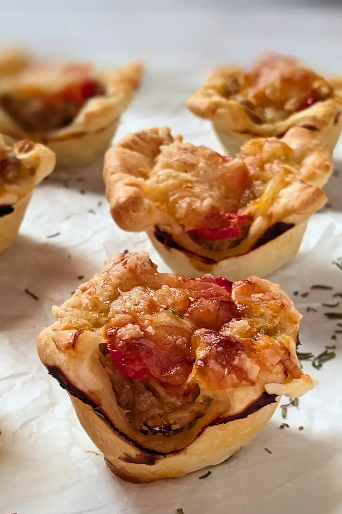 Mini Tuna Tart Cups With Puff Pastry - mini tuna tart appetizers made in a mini muffin tin with a canned tuna and sour cream filling and grated cheese topping in puff pastry cups.