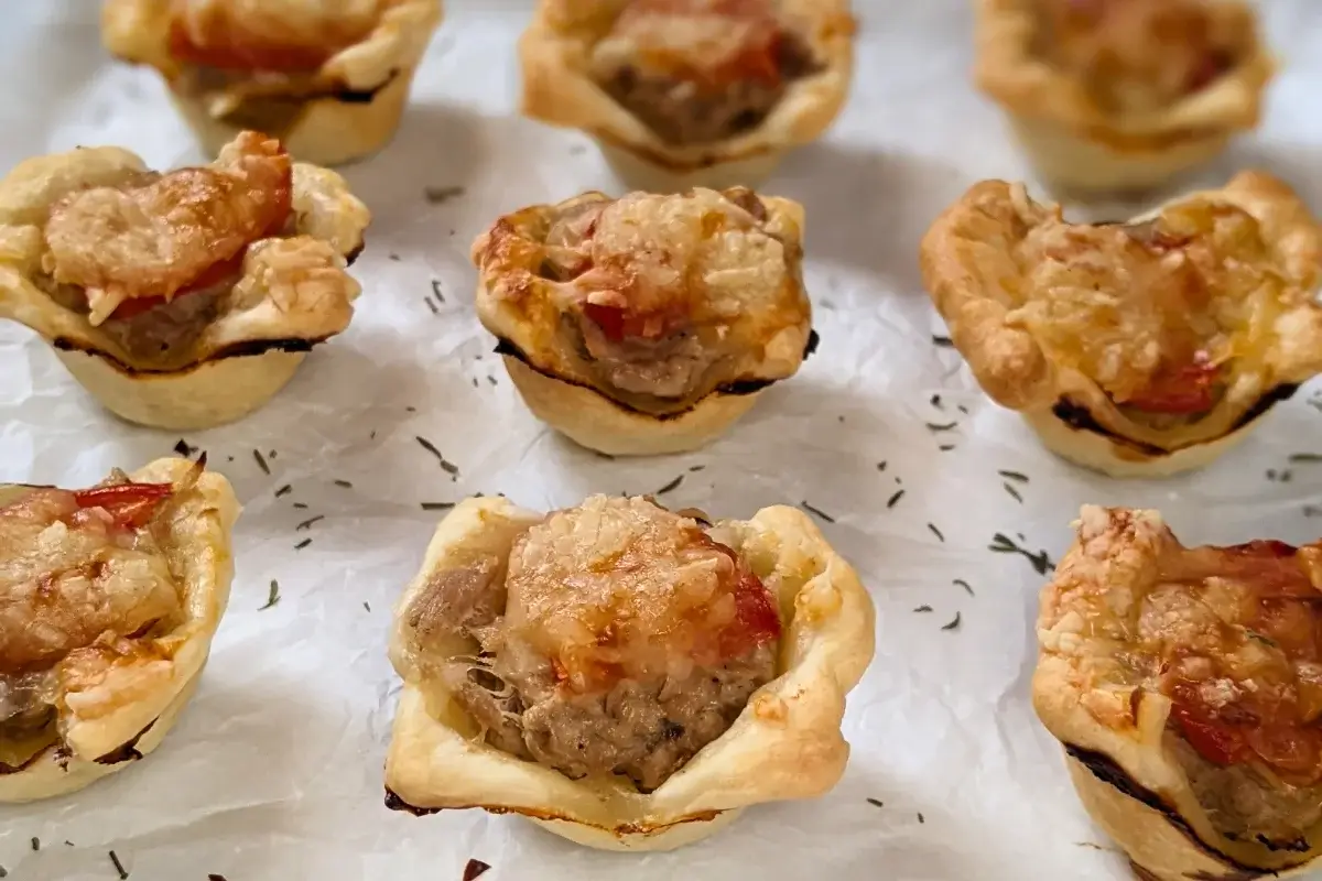 Mini Tuna Tart Cups With Puff Pastry - mini tuna tart appetizers made in a mini muffin tin with a canned tuna and sour cream filling and grated cheese topping in puff pastry cups.