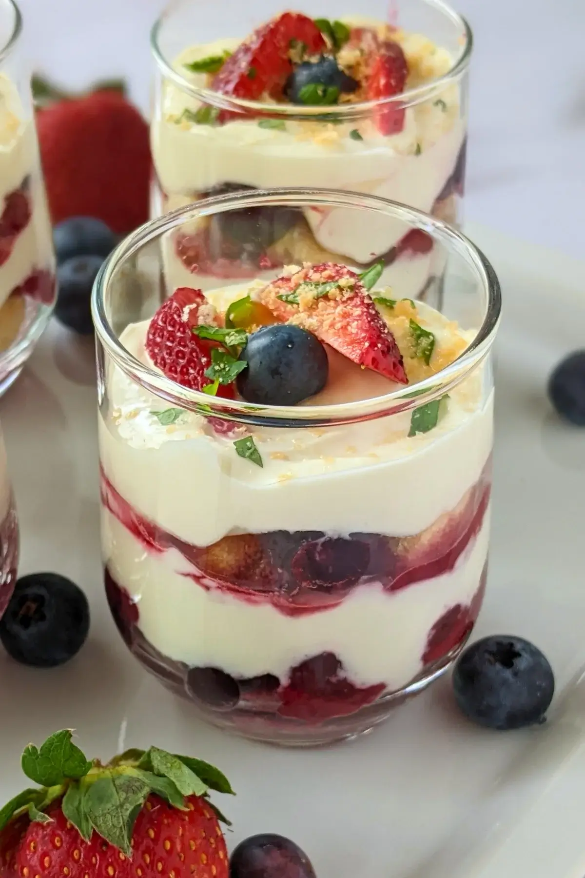 Mixed berry tiramisu in a glass dish with layers of mascarpone, Greek yogurt, and cooked berries like blueberries and strawberries.