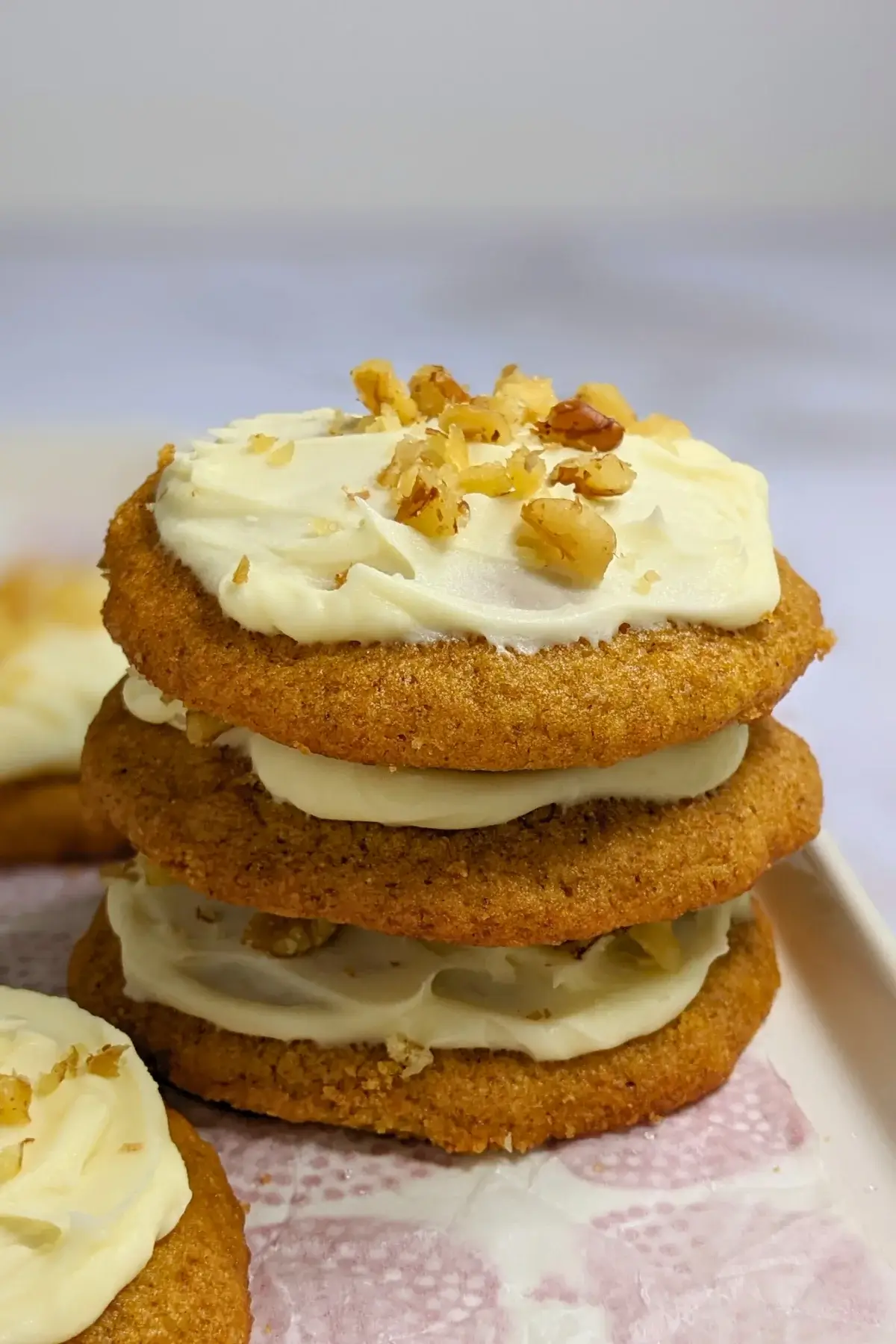 Pumpkin cookies with cream cheese icing made partly with healthier wholemeal flour and coconut sugar, frosted with a cream cheese icing and topped with crushed walnuts for decoration.