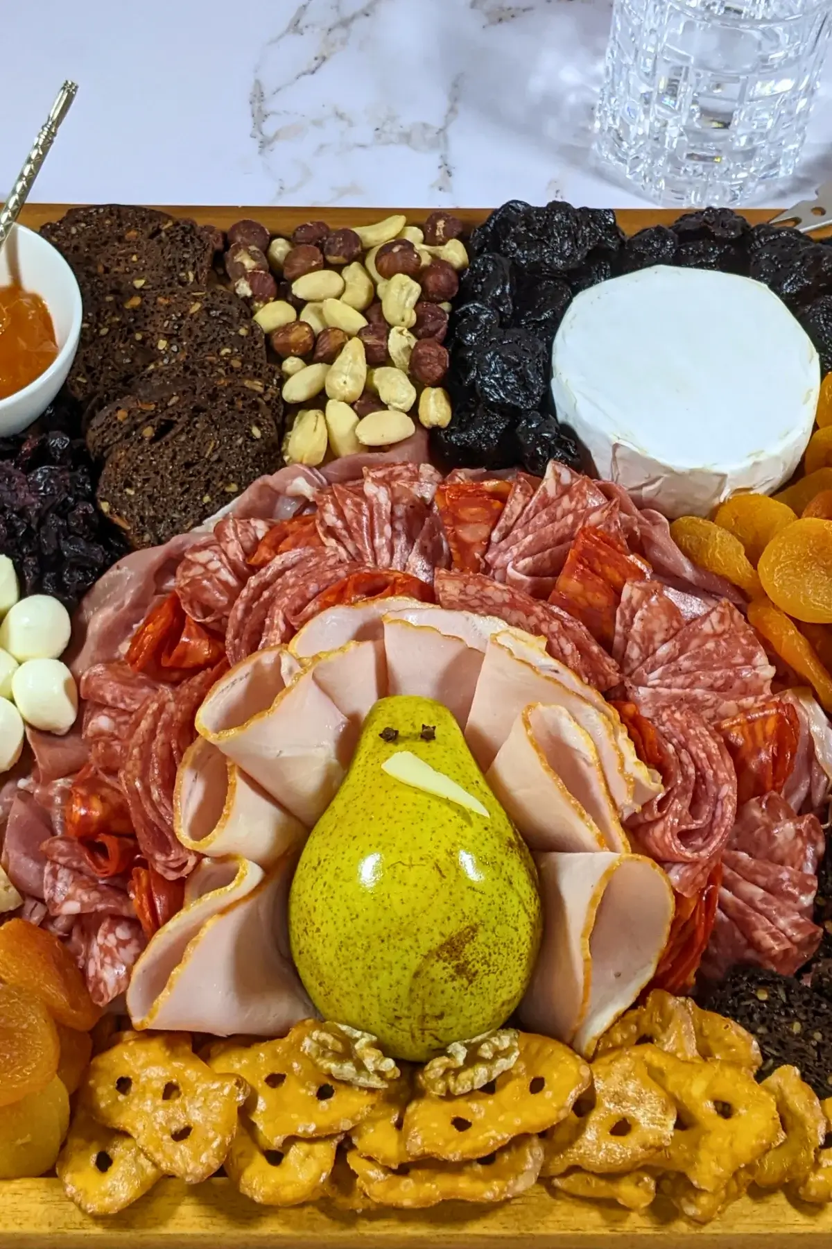 Turkey Charcuterie Board - fall themed turkey-shaped charcuterie board with different meats, cheeses, dried and fresh fruits, nuts, jams, and breads.
