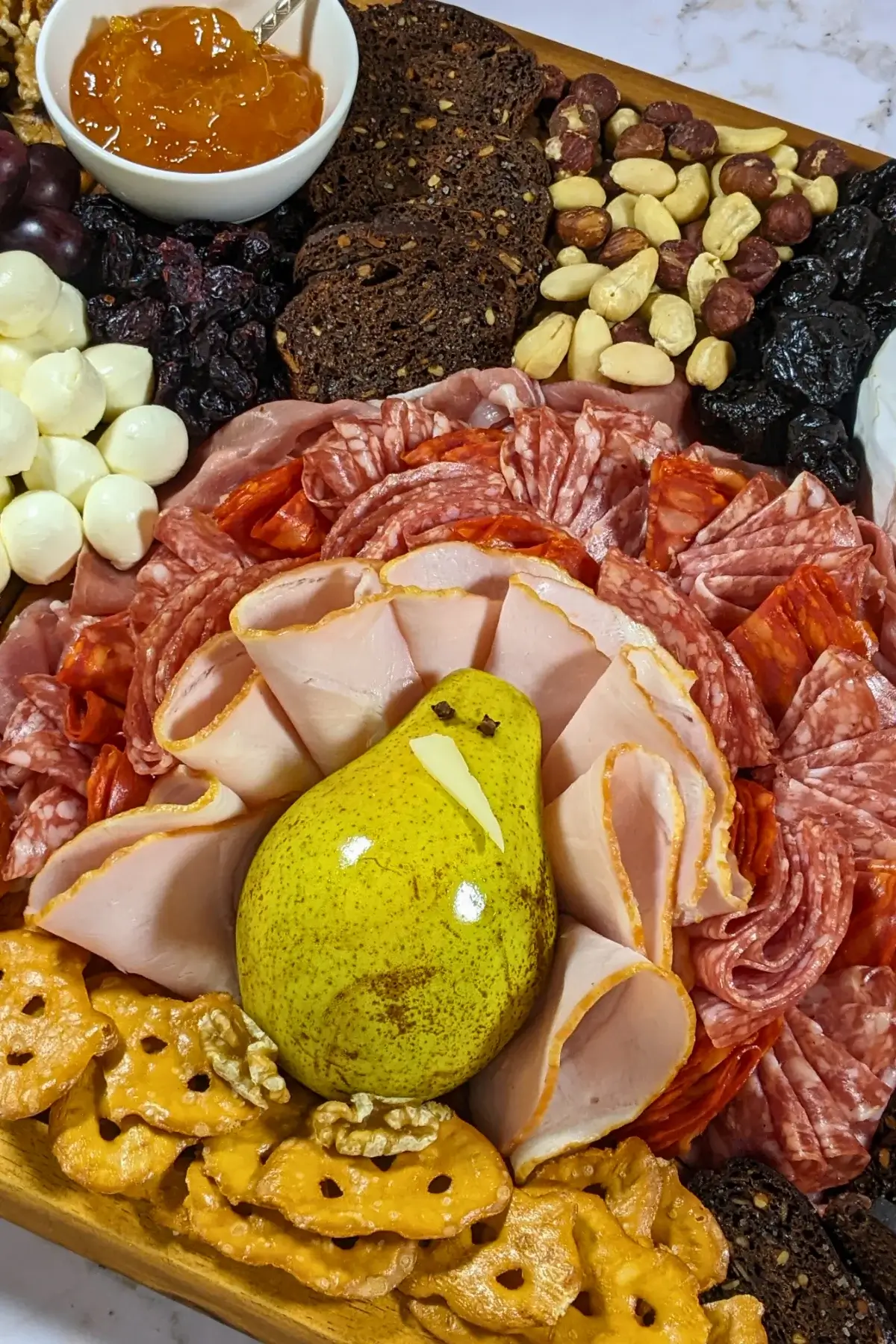 Turkey Charcuterie Board - fall themed turkey-shaped charcuterie board with different meats, cheeses, dried and fresh fruits, nuts, jams, and breads.