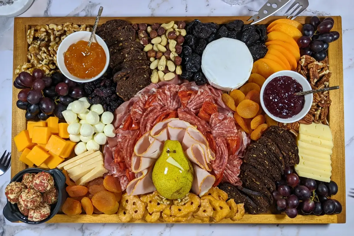 Turkey Charcuterie Board - fall themed turkey-shaped charcuterie board with different meats, cheeses, dried and fresh fruits, nuts, jams, and breads.