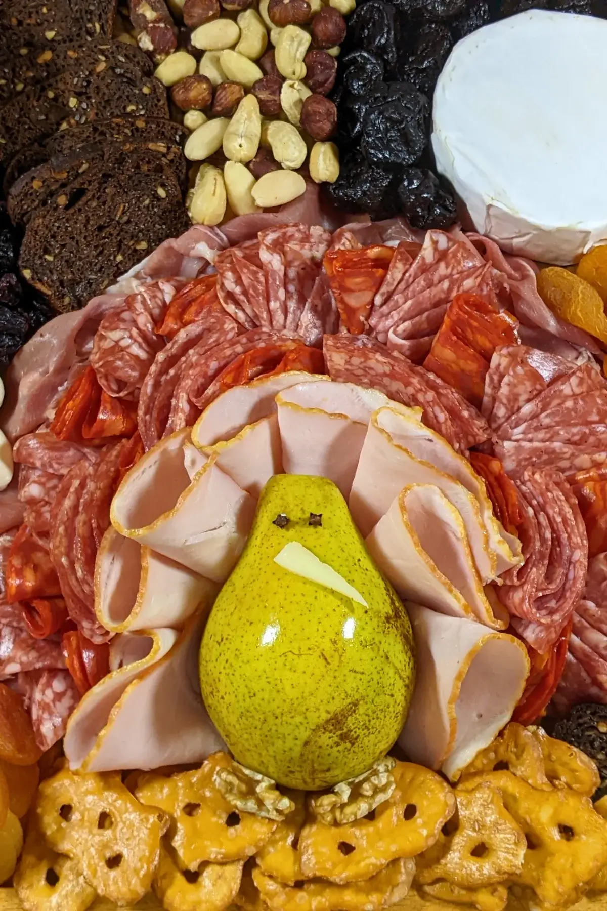 Turkey Charcuterie Board - fall themed turkey-shaped charcuterie board with different meats, cheeses, dried and fresh fruits, nuts, jams, and breads.