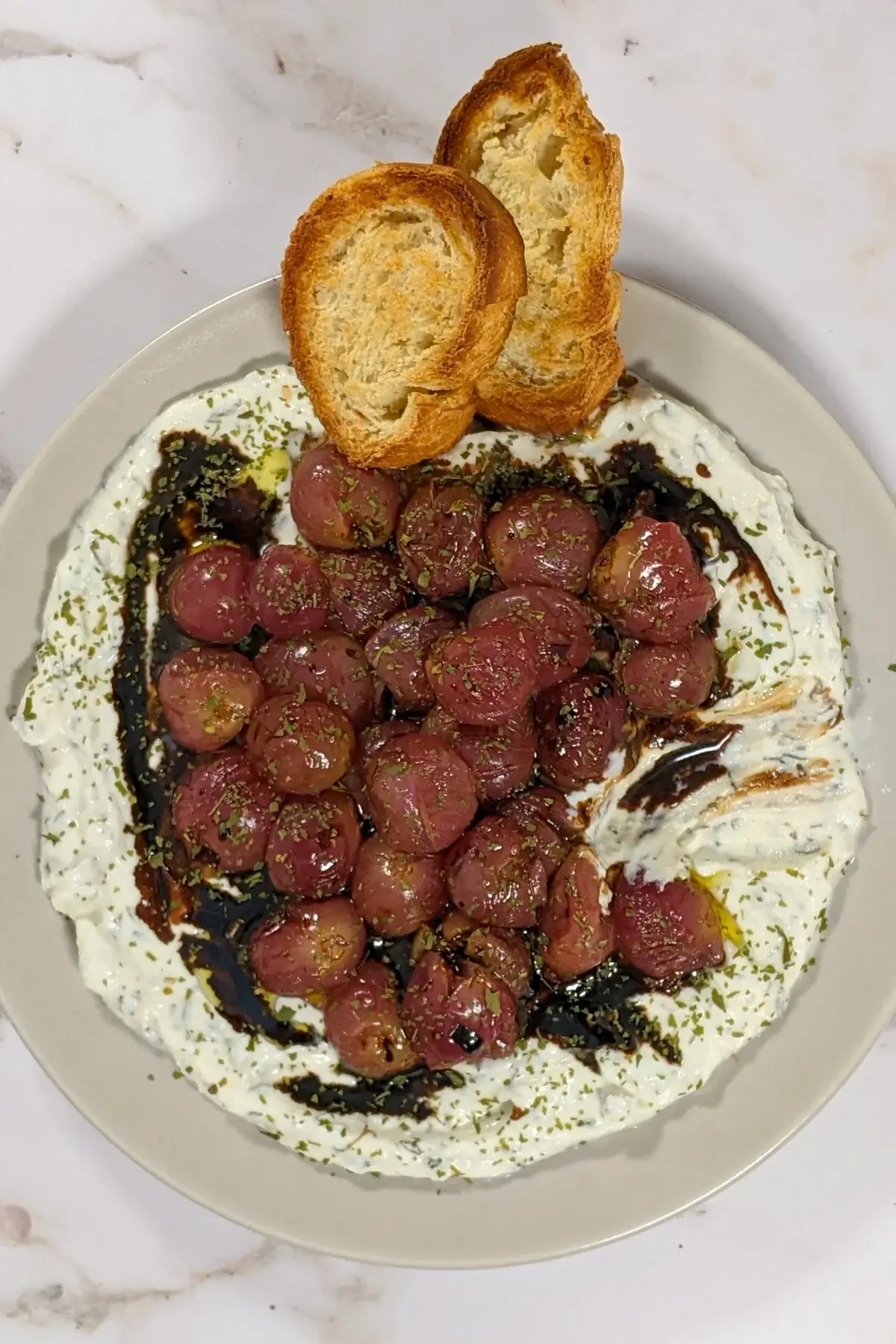 Whipped Ricotta Dip With Roasted Grapes - whipped ricotta blended with cream cheese, dried thyme, and dried garlic dip served with oven-roasted grapes on top and crispy French bread.