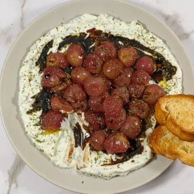 Whipped Ricotta Dip With Roasted Grapes - whipped ricotta blended with cream cheese, dried thyme, and dried garlic dip served with oven-roasted grapes on top and crispy French bread.