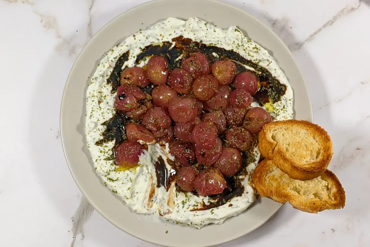Whipped Ricotta Dip With Roasted Grapes - whipped ricotta blended with cream cheese, dried thyme, and dried garlic dip served with oven-roasted grapes on top and crispy French bread.