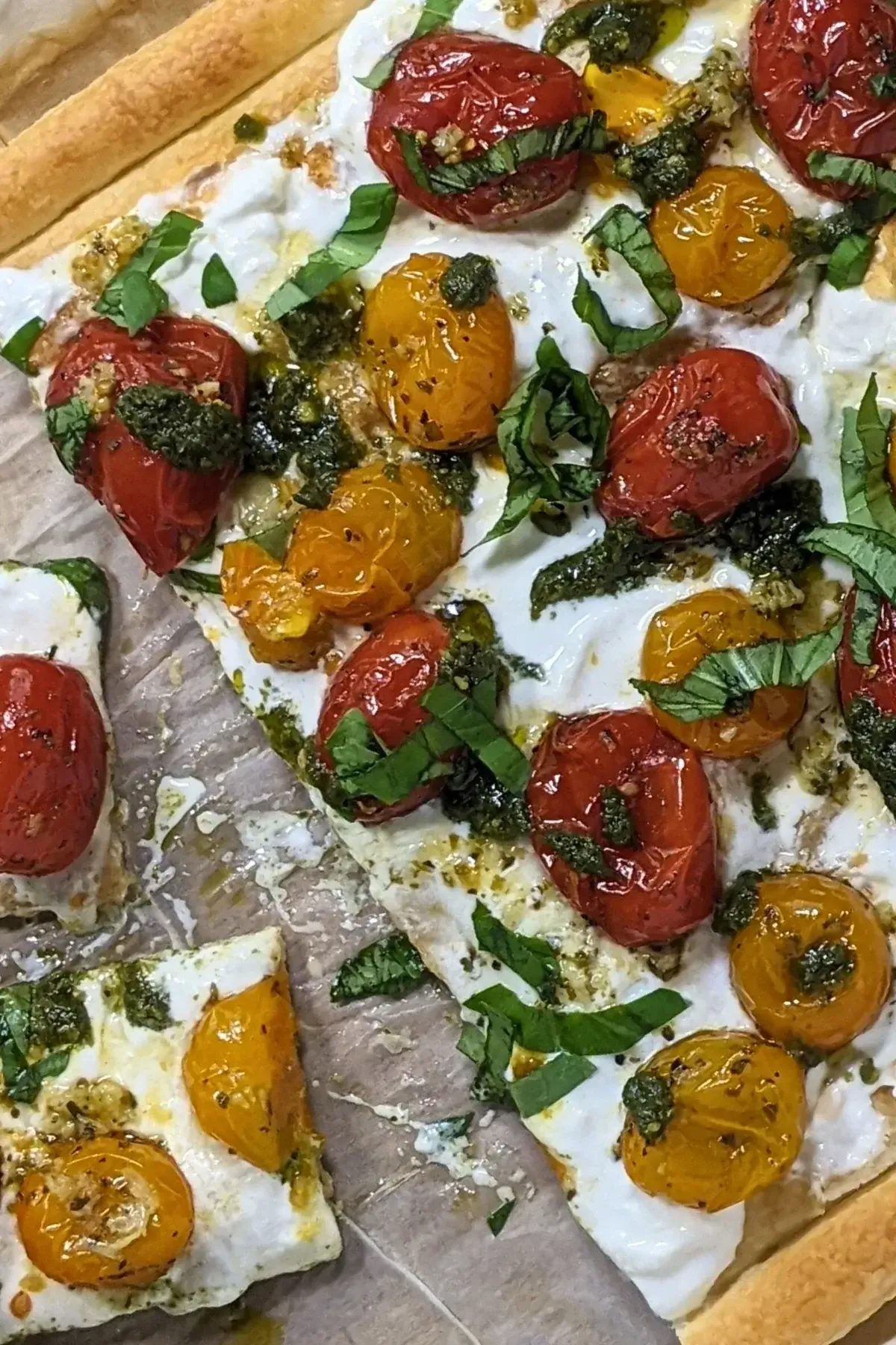 Cherry tomato and burrata appetizer with puff pastry, pesto, and fresh shredded basil.