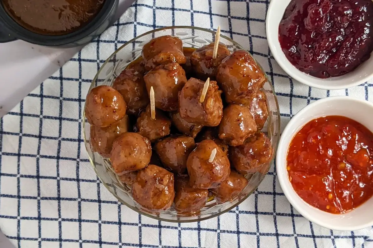 Cranberry Sausage Bites - sticky sausage appetizers made with pieces of fresh sausages, baked in the oven in a cranberry, sweet chili, soy sauce, and lime marinade.