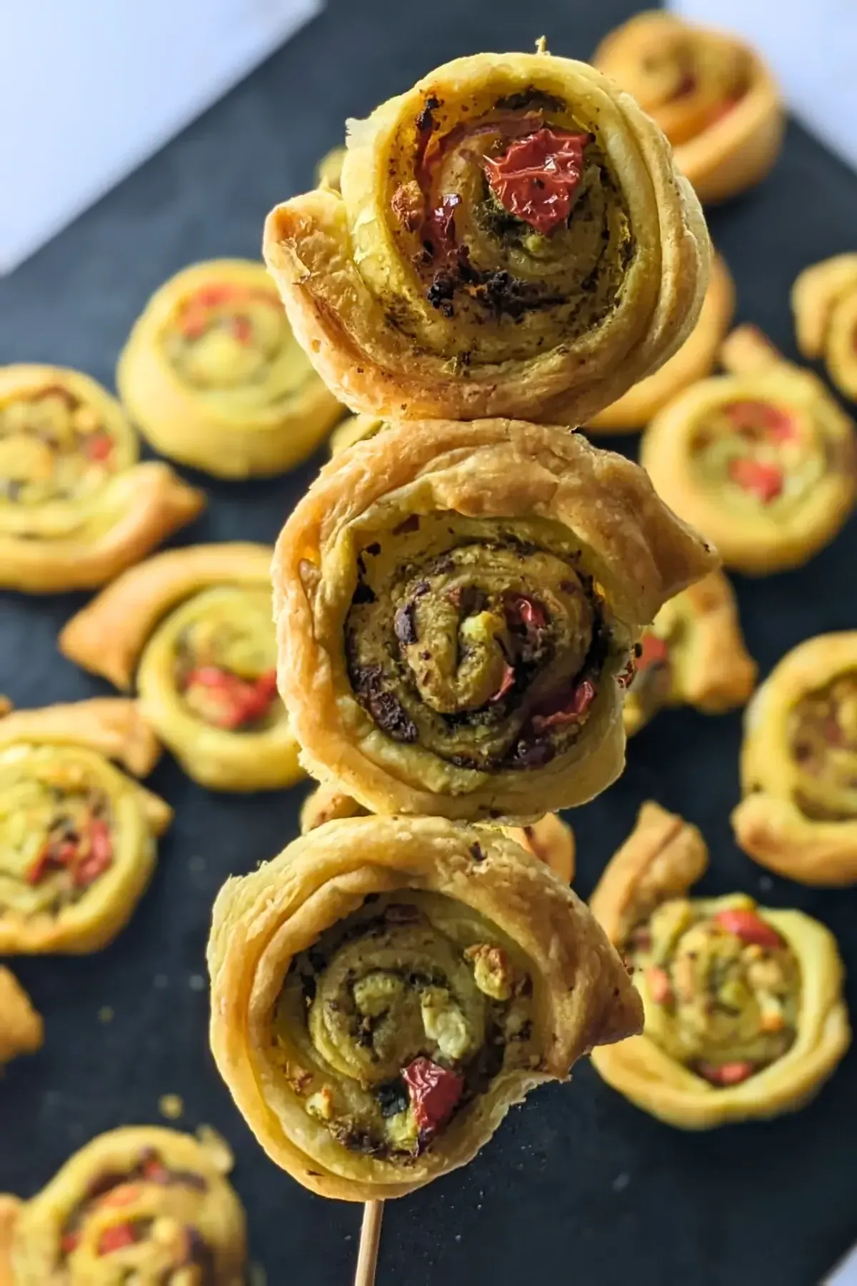 Pesto Pinwheels - Savory pesto pinwheels appetizers made with puff pastry and filled with basil pesto, fresh cherry tomatoes, and crumbled feta.