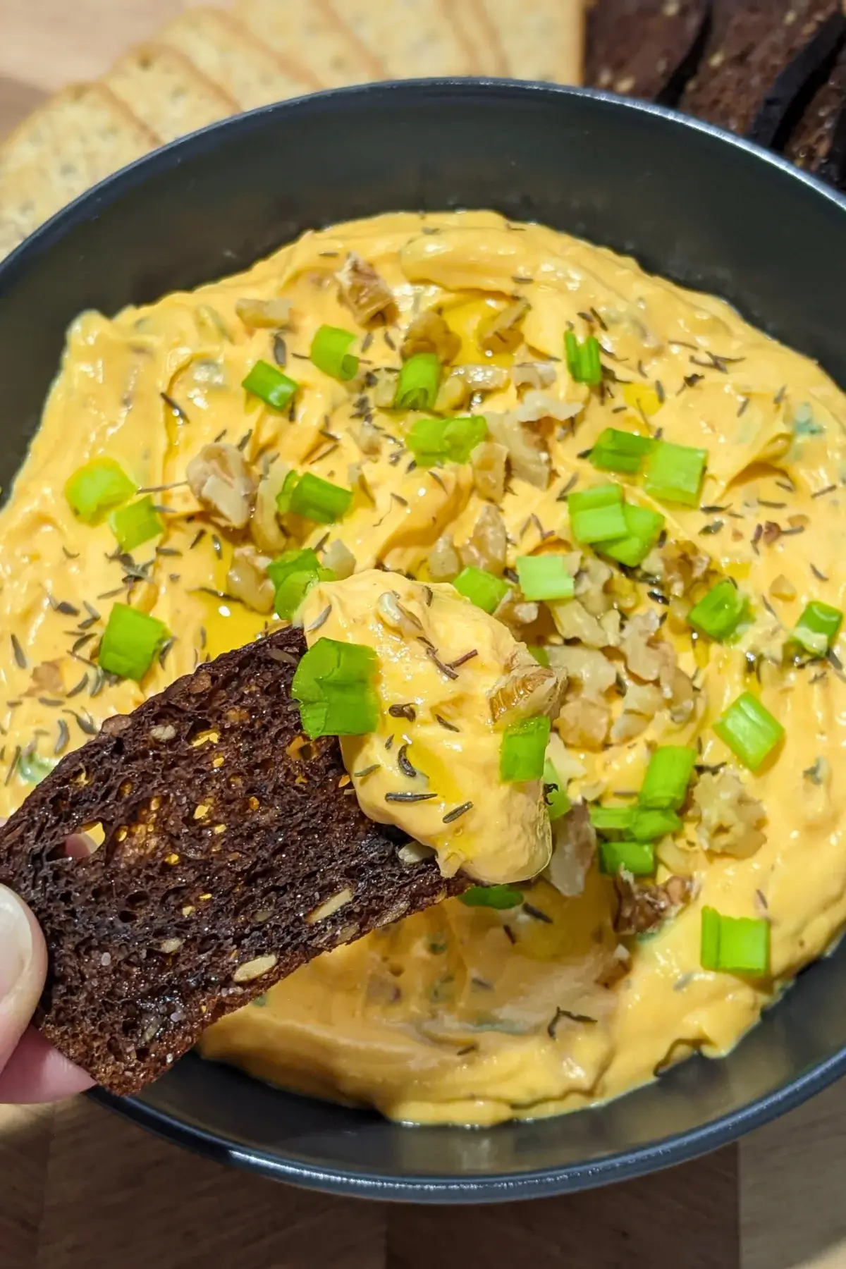 Pumpkin Feta Dip - party dip made with roasted pumpkin, feta cheese, a bit of Greek yoghurt, fried bacon, and green onion, served with green onion and crushed walnuts on top and crispbreads and crackers on the side.