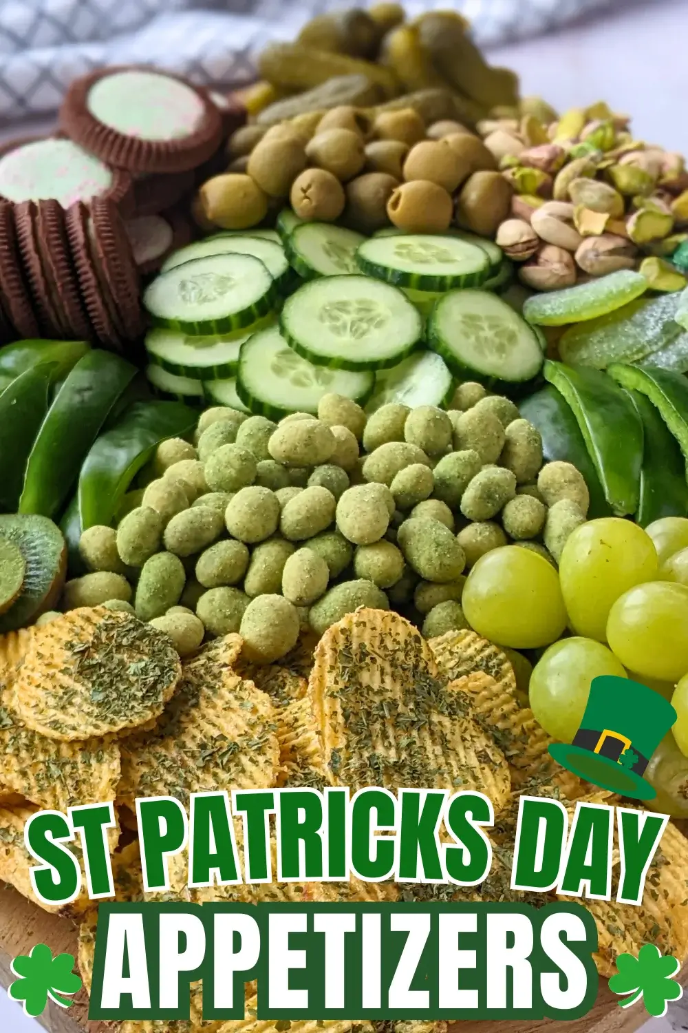 Green Food Board - Green themed party food board and snack tray with homemade tzatziki sauce and simple avocado dip; dried chives covered potato chips; crunchy wasabi coated peanuts; fresh cucumber and green capsicum; mini pickles; pistachios; olives in brine; fresh fruit like green grapes, green apples, kiwis, and green pears; and a selection of sweet snacks like green gummy candies and Domino's lime and peppermint cookies.