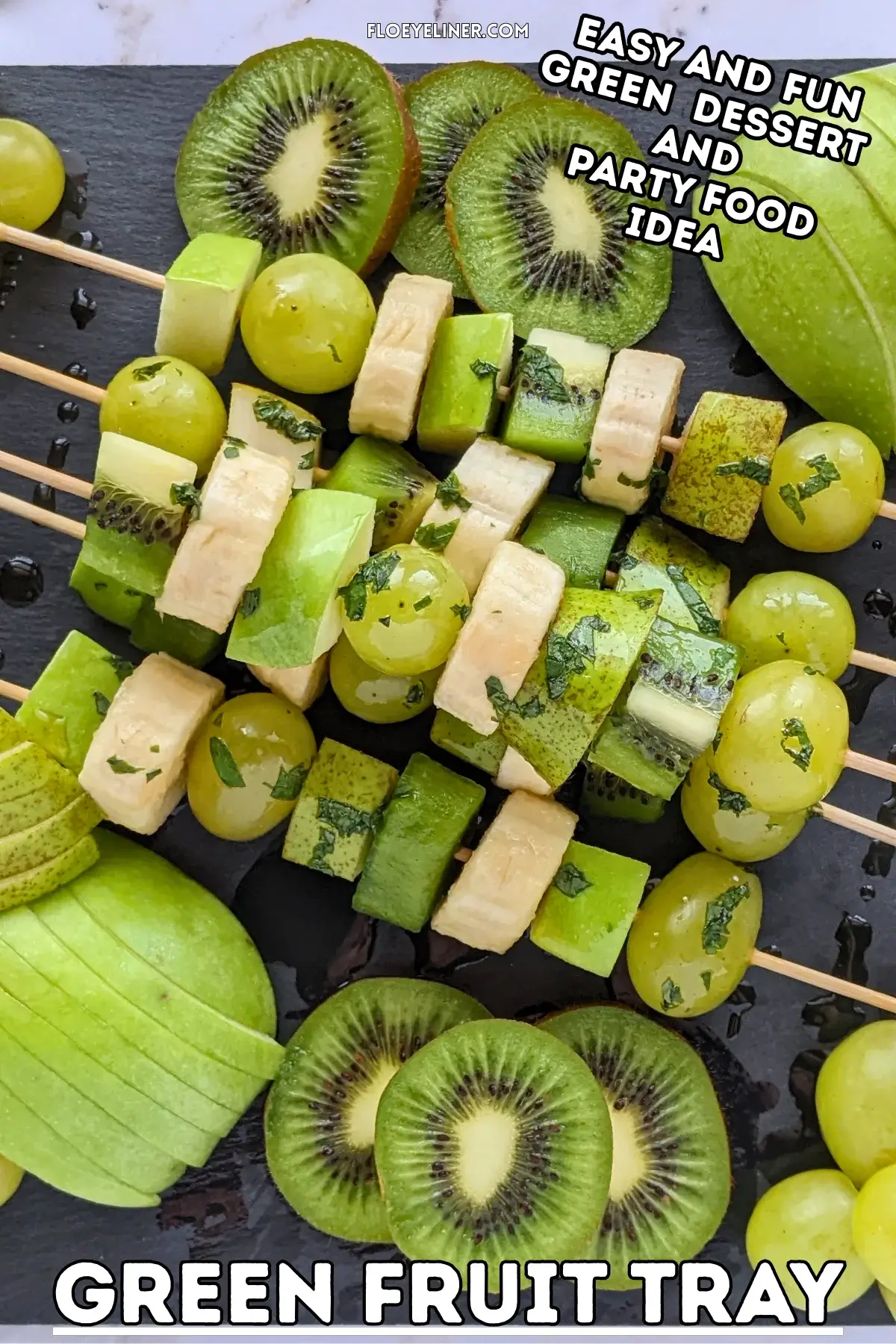 Green Fruit Tray - colorful green-themed fruit tray with green fruit kabobs featuring fruits like kiwi, green grapes, green apple, green pear, and bananas that are drizzled with a fresh mint, lime juice, and maple sryup sauce, plus slices of green apple, green pear, kiwis, and little piles of green grapes. 