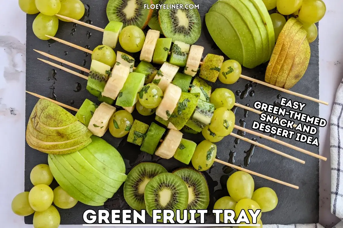 Green Fruit Tray - colorful green-themed fruit tray with green fruit kabobs featuring fruits like kiwi, green grapes, green apple, green pear, and bananas that are drizzled with a fresh mint, lime juice, and maple sryup sauce, plus slices of green apple, green pear, kiwis, and little piles of green grapes.