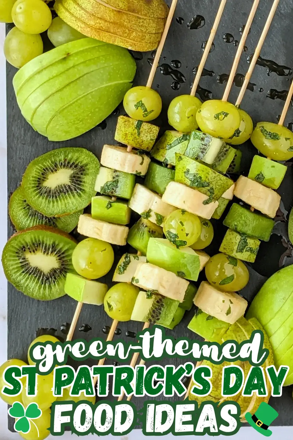 Green Fruit Tray - colorful green-themed fruit tray with green fruit kabobs featuring fruits like kiwi, green grapes, green apple, green pear, and bananas that are drizzled with a fresh mint, lime juice, and maple sryup sauce, plus slices of green apple, green pear, kiwis, and little piles of green grapes.