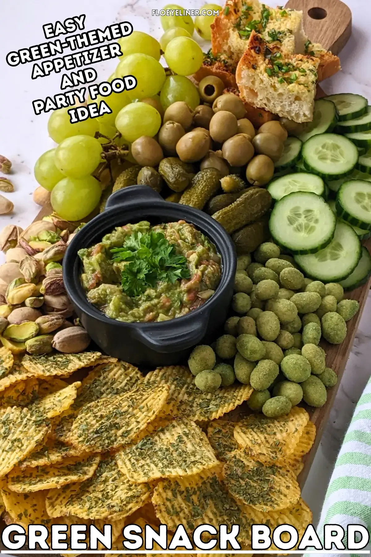 Green Snack Board - Green themed snack board and party tray with homemade garlic bread and guacamole dip, dried chives covered potato chips, fresh cucumbers, mini pickles, olives, pistachios, crunchy wasabi coated peanuts, and green grapes.