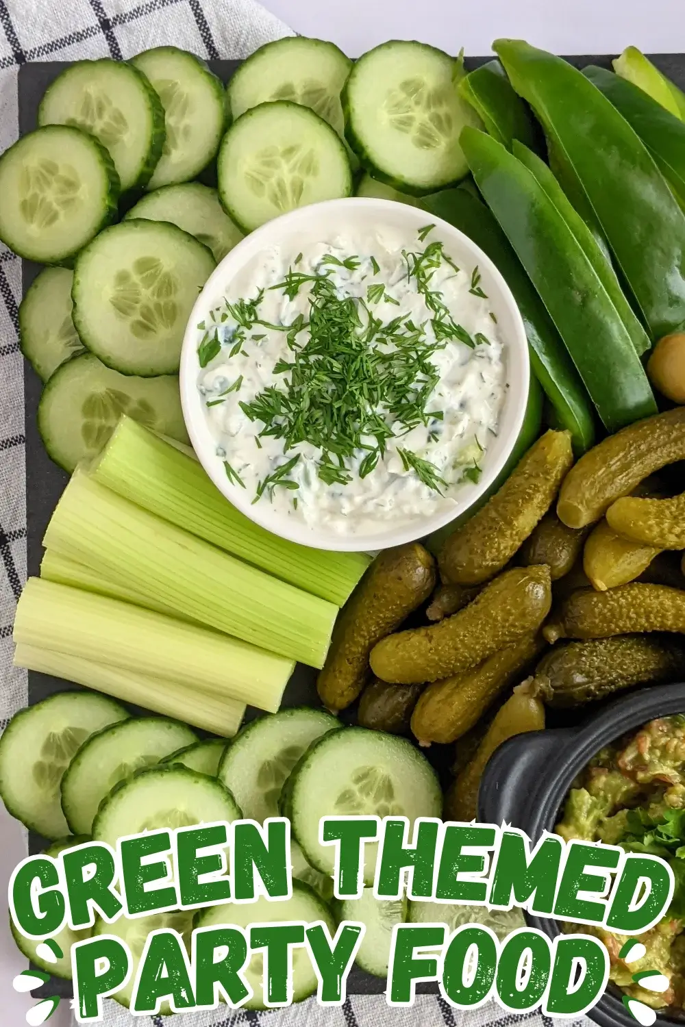 Green Veggie Tray - Green themed vegetable board with homemade guacamole and tzatziki sauce; fresh vegetables like cucumber, green capsicum, celery, frillice lettuce, and avocado; and pickled foods like mini pickles, jalapenos, and olives in brine.