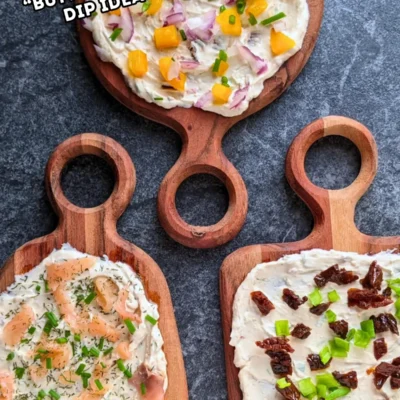 Trio of whipped feta board appetizers, one topped with smoked salmon and fresh chives, the other with sun-dried tomatoes and fresh green onions, and the third with yellow bell peppers, red onion, and fresh chives, all on a creamy feta dip base.