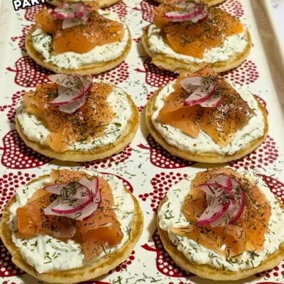 Mini Pancake Smoked Salmon Appetizers - savory mini pancake canapes topped with a creamy lemon-dill cream cheese spread, pieces of smoked salmon, and radish slices for garnish.