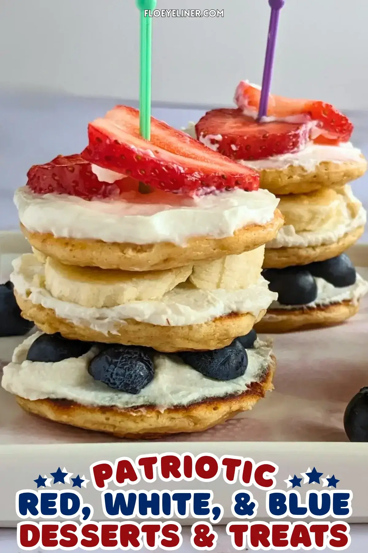 Pancake Stacks With Fresh Blueberries and Strawberries - small pancakes spread with sweet ricotta and layered in a stack with blueberries in the bottom layer, banana slices in the middle, and strawberries at the top, secured with toothpicks.