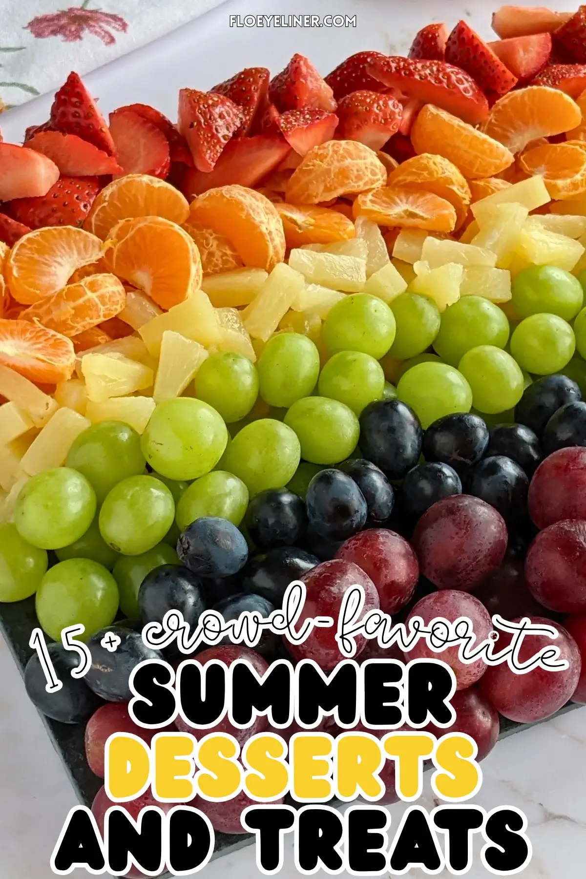 Rainbow Fruit Tray - colorful fruit platter in rainbow colors made with fruits and berries like strawberries, mandarin segments, canned pineapple pieces, green grapes, blue grapes, and dark red grapes.