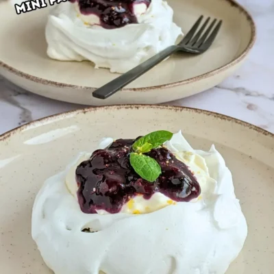 Lemon Blueberry Mini Pavlovas With Cheesecake Filling - mini pavlova nests filled with homemade lemon blueberry jam and a lemony cheesecake filling, topped with more blueberry jam and lemon zest for garnish.