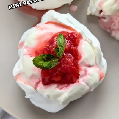 Mini Strawberry Pavlovas With Whipped Greek Yogurt - mini pavlova nests filled with freshly crushed strawberries and a whipped cream-Greek yogurt mix, topped with more crushed strawberries and strawberry juice for garnish.