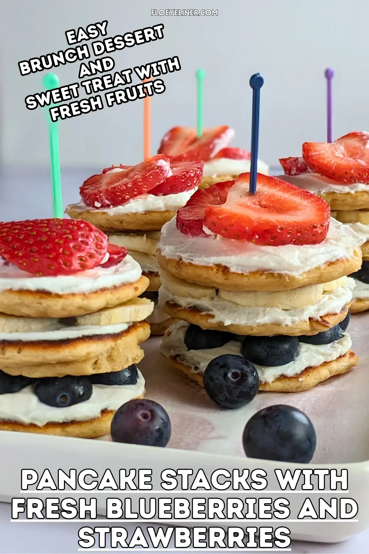 Pancake Stacks With Fresh Blueberries and Strawberries - small pancakes spread with sweet ricotta and layered in a stack with blueberries in the bottom layer, banana slices in the middle, and strawberries at the top, secured with toothpicks.