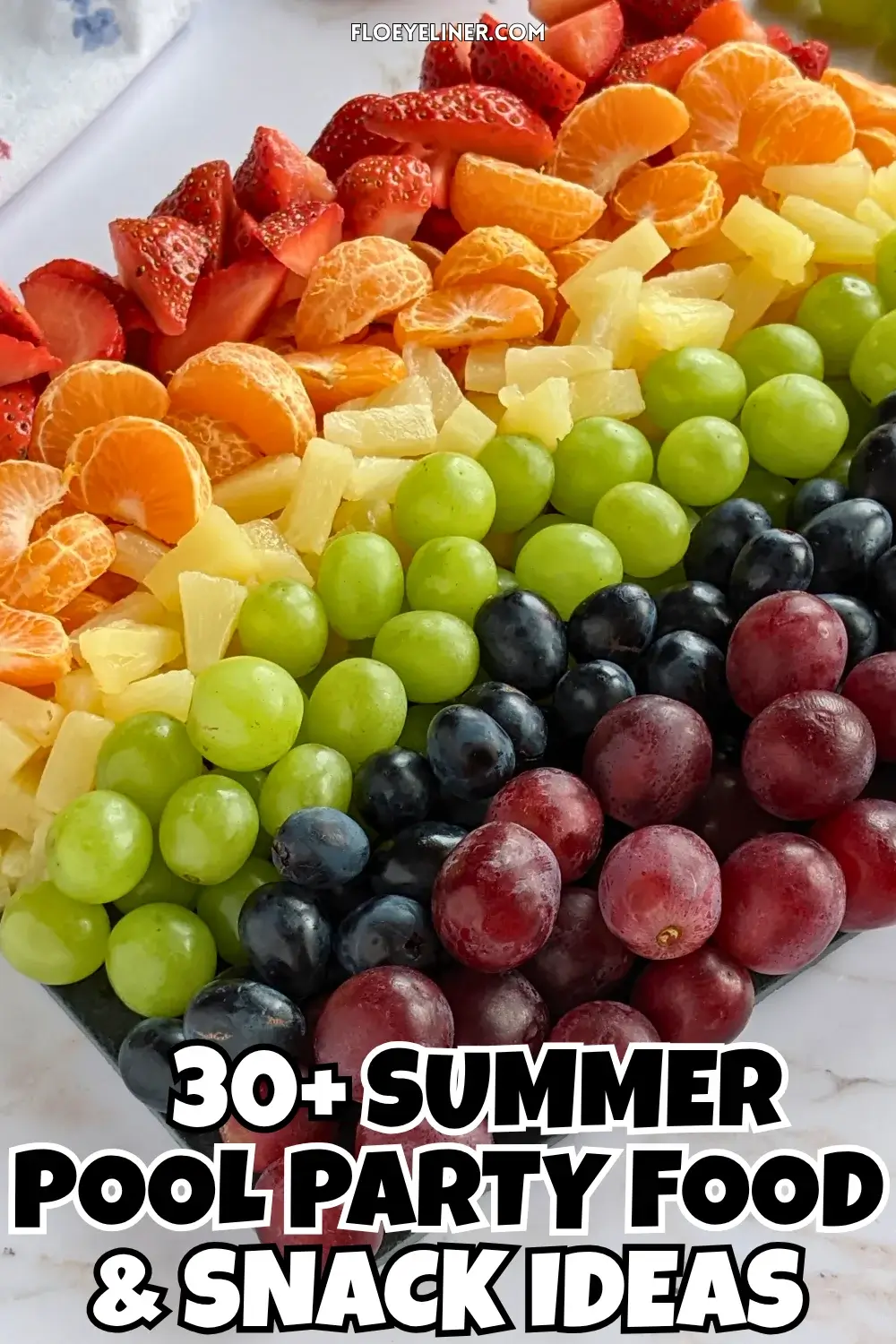Rainbow Fruit Tray - colorful fruit platter in rainbow colors made with fruits and berries like strawberries, mandarin segments, canned pineapple pieces, green grapes, blue grapes, and dark red grapes.