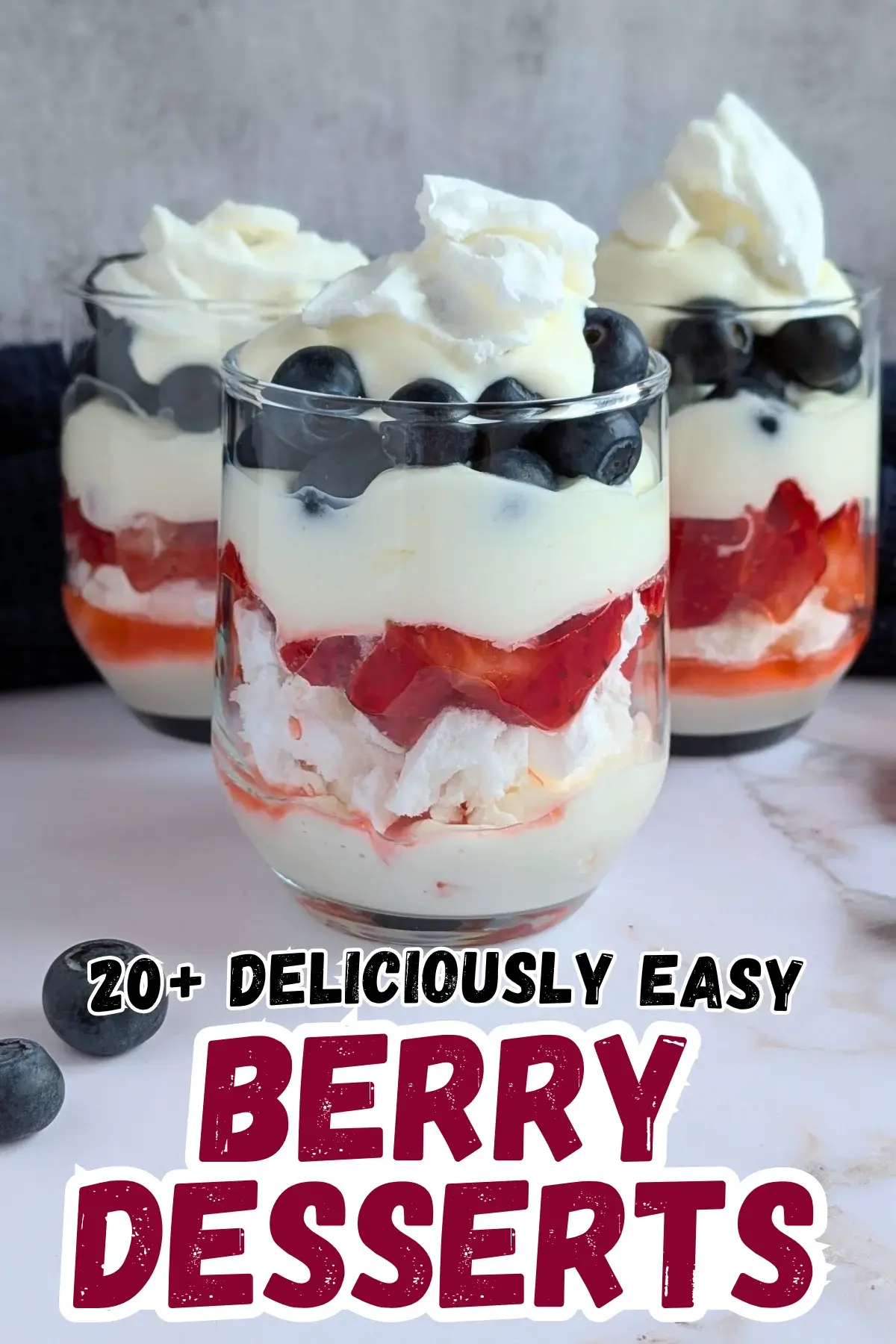 Mixed Berry Eton Mess Desserts - individual eton mess dessert cups, made with layers of mascarpone-whipped cream mix, crushed meringue, fresh strawberries, another layer of mascarpone-whipped cream mix, fresh blueberries, and topped with more cream and crushed meringue.